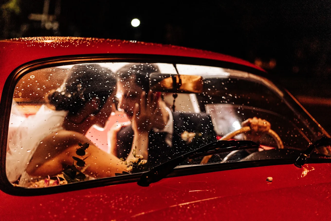 Casal de noivos dentro do carro em noite de chuva